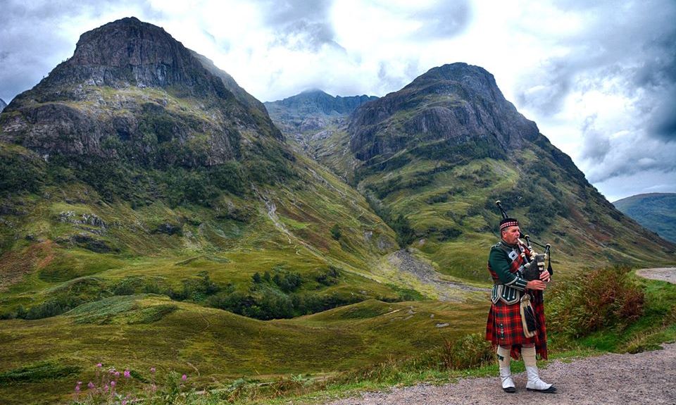 Piper with Gearr Aonach and Aonach Dubh in Glencoe